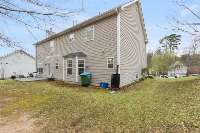 back of property featuring a patio area, a yard, and a chimney