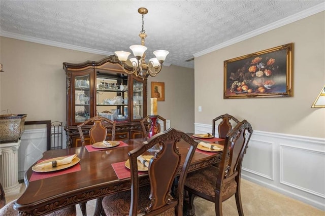 carpeted dining space with an inviting chandelier, a textured ceiling, and a wainscoted wall