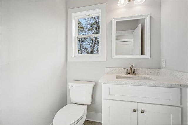 bathroom featuring baseboards, vanity, and toilet