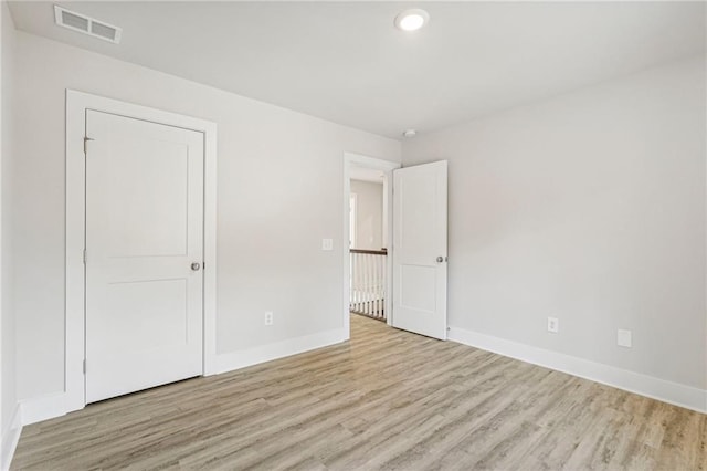 unfurnished bedroom featuring wood finished floors, visible vents, and baseboards