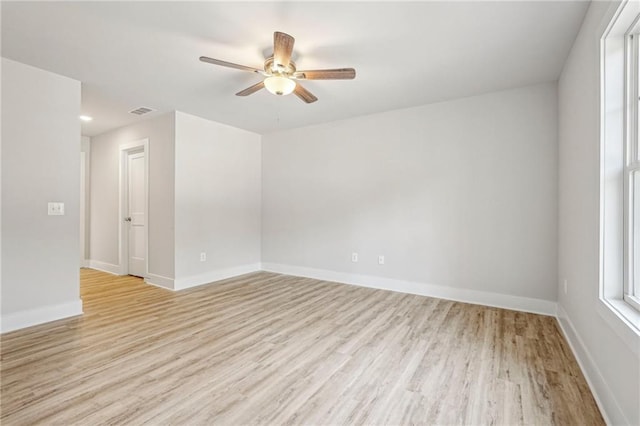 spare room featuring a ceiling fan, light wood-type flooring, visible vents, and baseboards