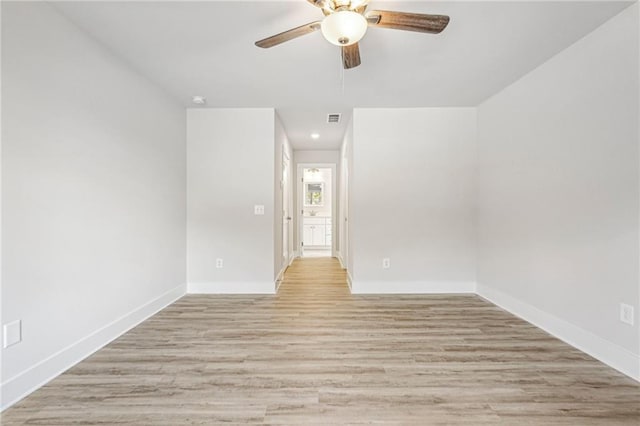 spare room featuring baseboards, a ceiling fan, visible vents, and light wood-style floors