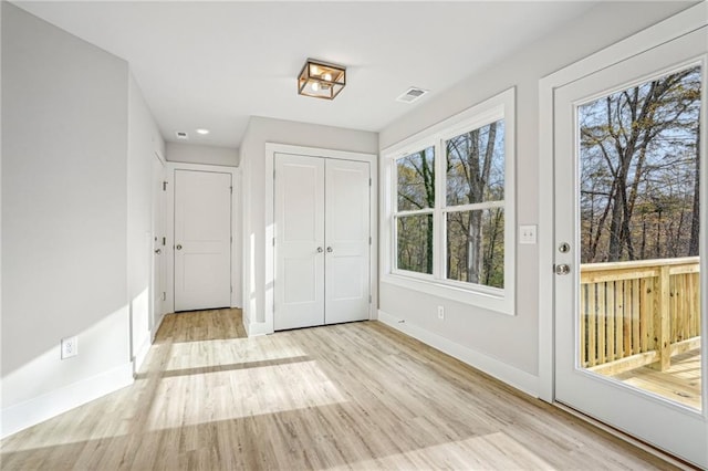 doorway to outside with a wealth of natural light, visible vents, baseboards, and wood finished floors