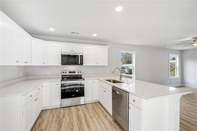 kitchen featuring stainless steel appliances, a peninsula, a sink, visible vents, and light wood-type flooring