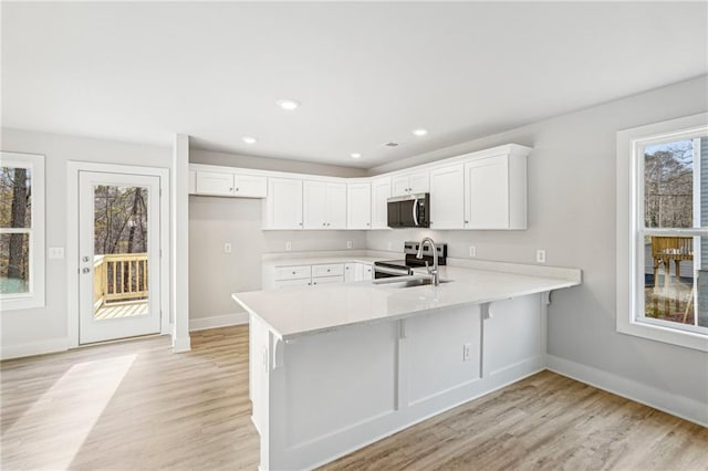 kitchen featuring appliances with stainless steel finishes, light countertops, a sink, and a peninsula