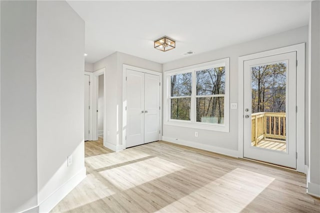 interior space with baseboards, access to outside, visible vents, and wood finished floors