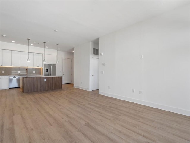 675 Drewry St NE Unit 205, Atlanta, GA 30306 - kitchen featuring stainless steel appliances, open floor plan, white cabinets, light wood-style flooring, and a kitchen island