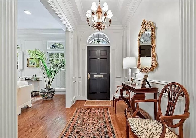 foyer with crown molding, a chandelier, and hardwood / wood-style floors