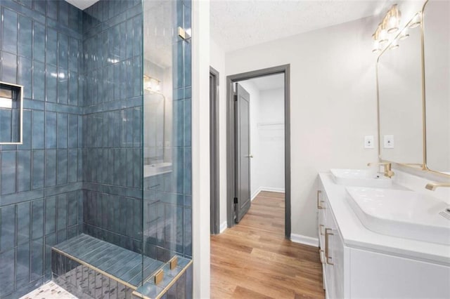 bathroom featuring a tile shower, vanity, wood-type flooring, and a textured ceiling