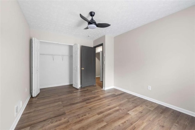 unfurnished bedroom featuring a textured ceiling, ceiling fan, dark wood-type flooring, and a closet