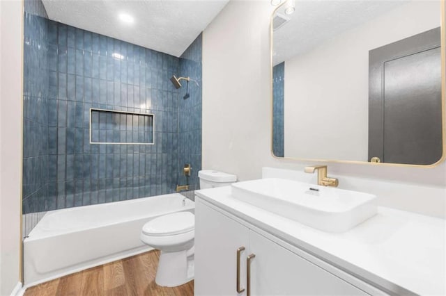 full bathroom featuring vanity, a textured ceiling, wood-type flooring, toilet, and tiled shower / bath