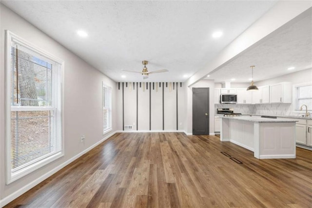 unfurnished living room featuring light hardwood / wood-style floors, ceiling fan, and a healthy amount of sunlight