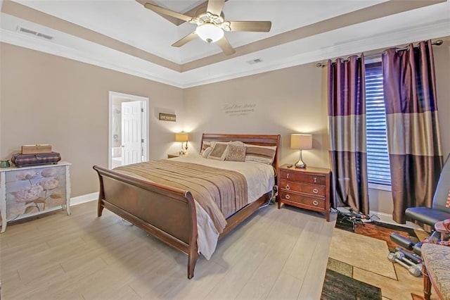 bedroom featuring light wood finished floors, visible vents, ornamental molding, and baseboards