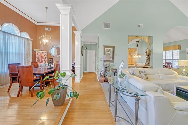 living room featuring crown molding, visible vents, decorative columns, and an inviting chandelier