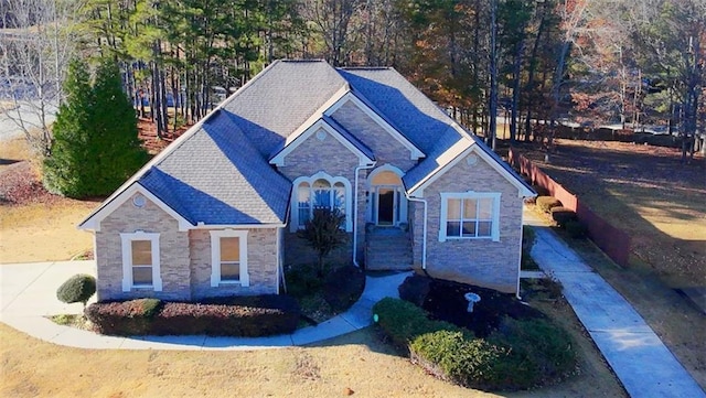 view of front facade featuring stone siding and a shingled roof