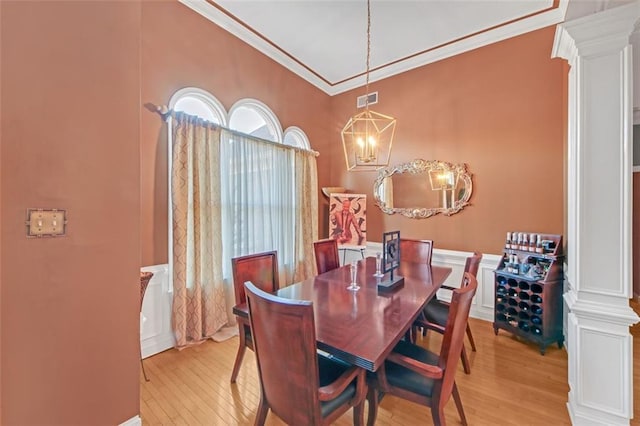 dining room with crown molding, light wood-style flooring, visible vents, and ornate columns