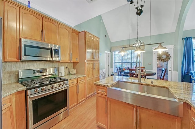 kitchen with light stone counters, stainless steel appliances, backsplash, vaulted ceiling, and a sink