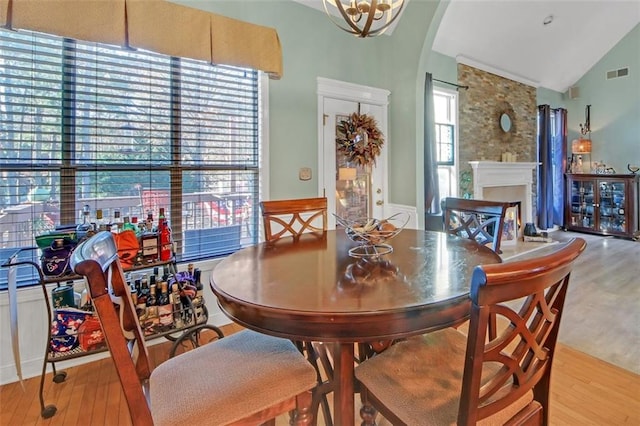 dining space with lofted ceiling, arched walkways, wood finished floors, and visible vents