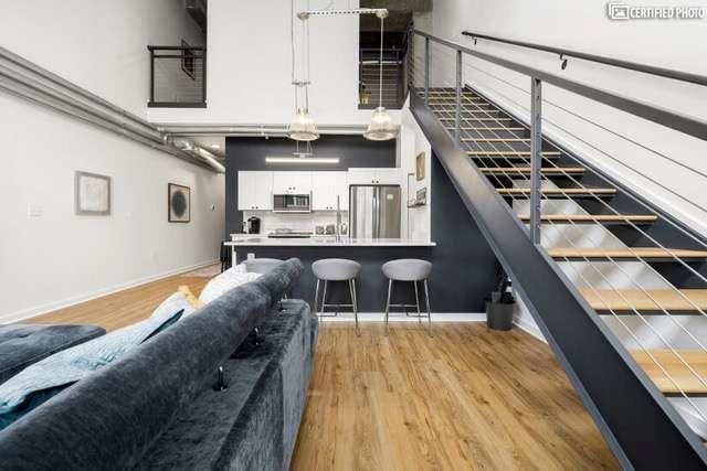 bar featuring hanging light fixtures, appliances with stainless steel finishes, white cabinets, and light wood-type flooring