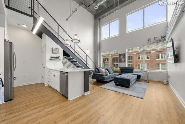 kitchen with a towering ceiling, stainless steel appliances, light hardwood / wood-style floors, and white cabinets