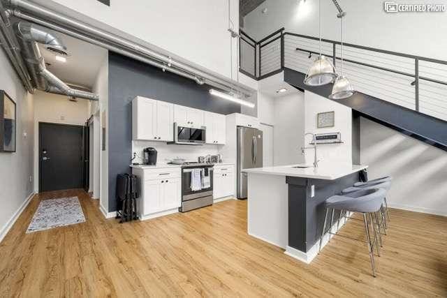 kitchen featuring a towering ceiling, pendant lighting, white cabinetry, a kitchen breakfast bar, and stainless steel appliances