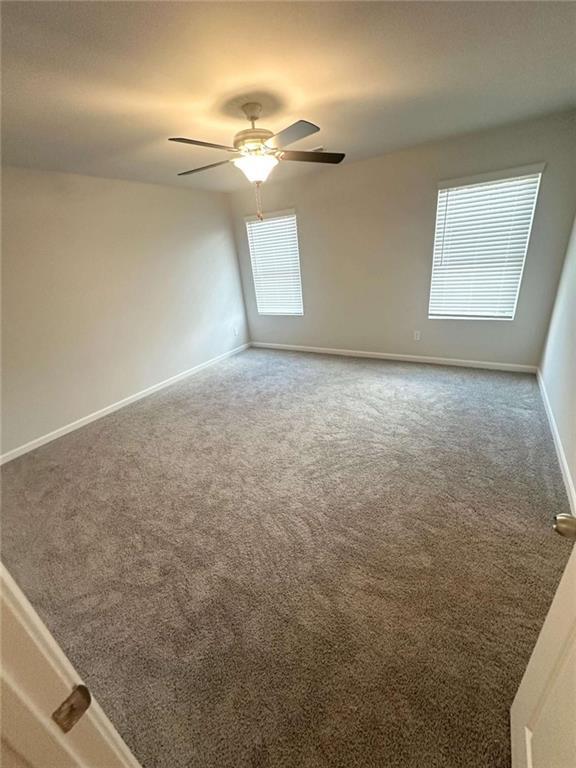 carpeted spare room with baseboards and ceiling fan