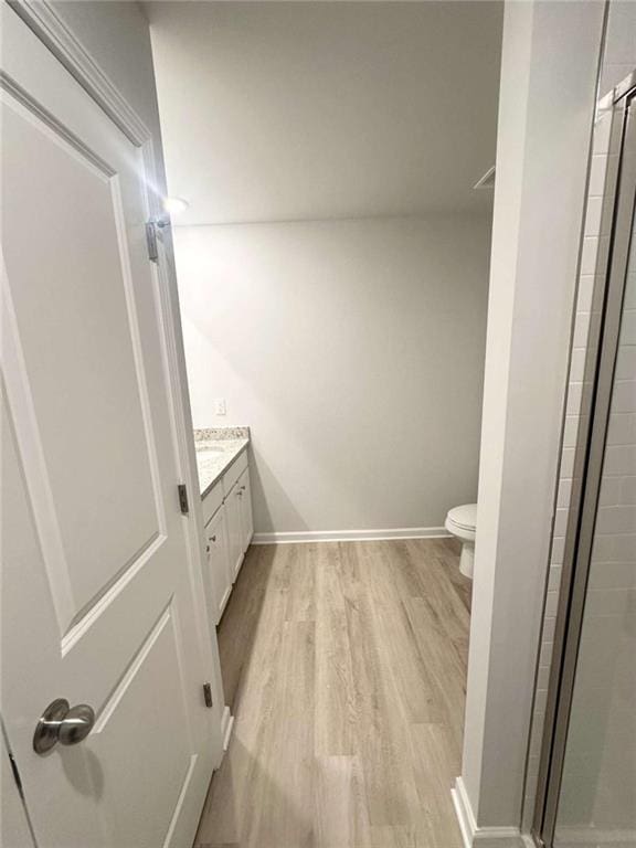 bathroom featuring vanity, wood finished floors, baseboards, a stall shower, and toilet