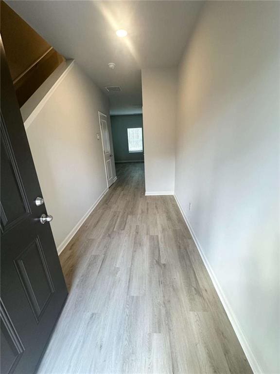 hall with baseboards and light wood finished floors