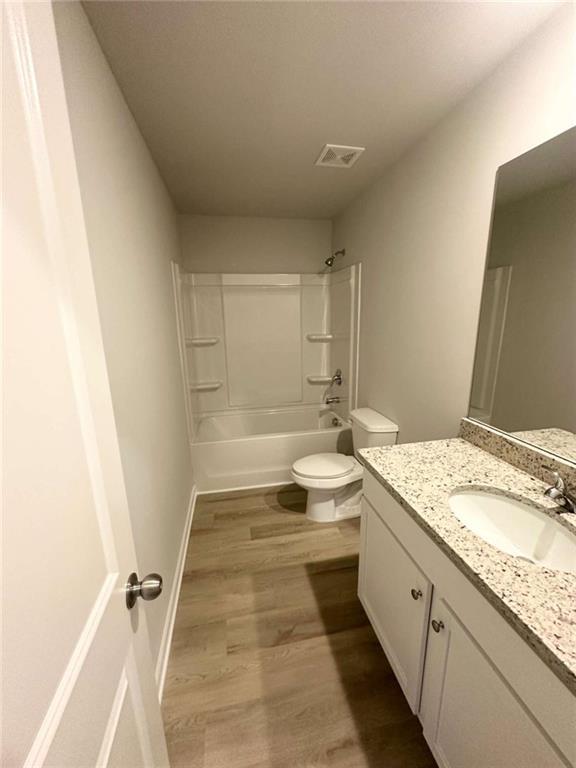 full bathroom with vanity, wood finished floors, visible vents, toilet, and shower / bathtub combination