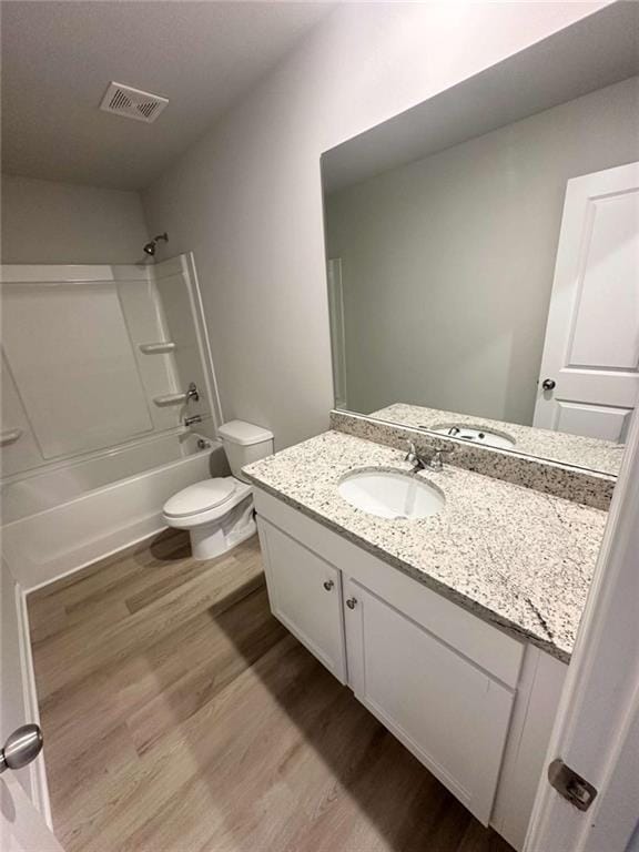 bathroom with visible vents, tub / shower combination, toilet, wood finished floors, and vanity