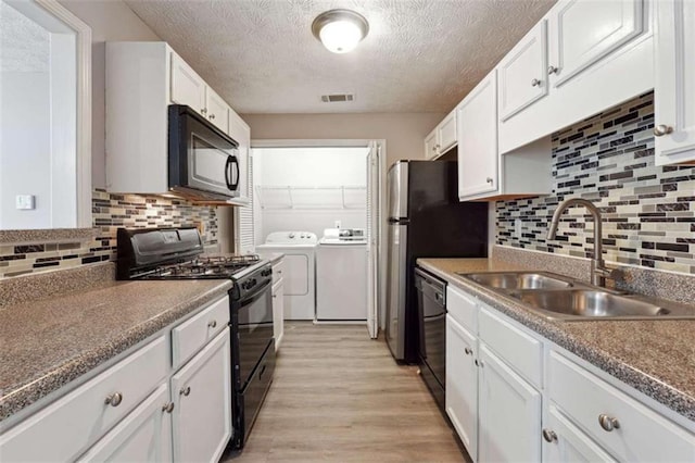 kitchen featuring independent washer and dryer, black appliances, tasteful backsplash, white cabinets, and sink