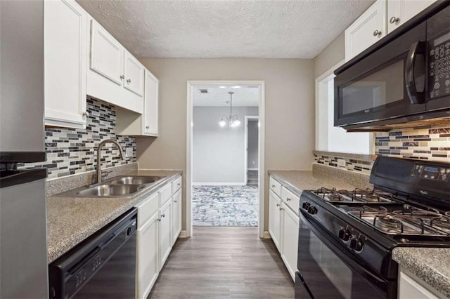 kitchen featuring dark wood-type flooring, a notable chandelier, black appliances, white cabinetry, and sink