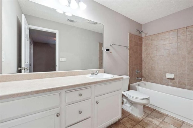 full bathroom featuring toilet, vanity, a textured ceiling, and tiled shower / bath