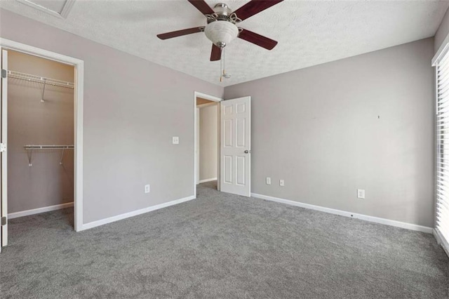 unfurnished bedroom with a closet, ceiling fan, a spacious closet, and carpet flooring