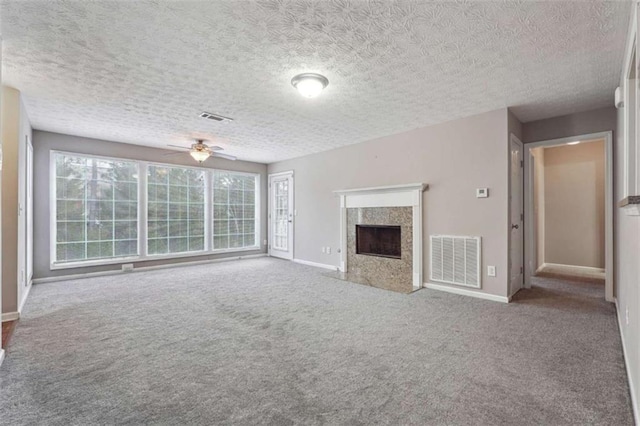 unfurnished living room with a premium fireplace, ceiling fan, a textured ceiling, and carpet flooring