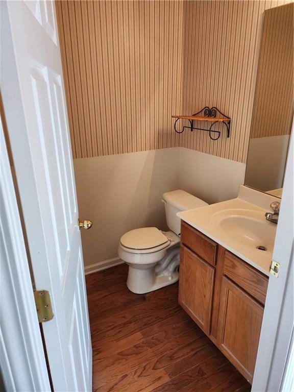 half bathroom with vanity, toilet, and wood finished floors