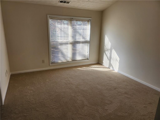 carpeted empty room with visible vents, a textured ceiling, and baseboards