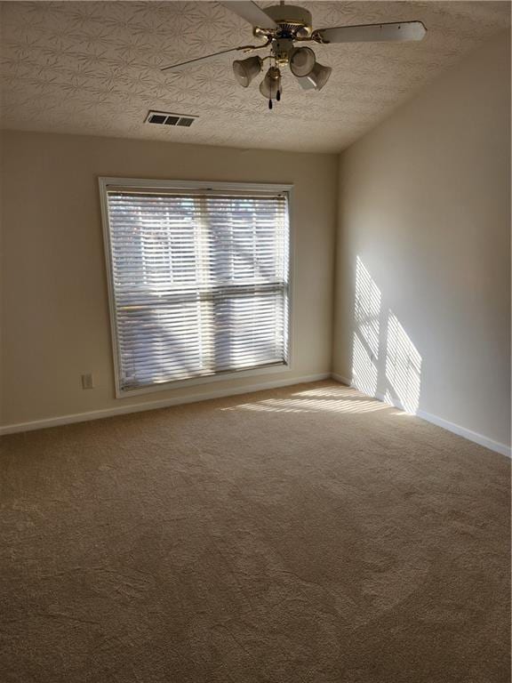 carpeted spare room with baseboards, visible vents, ceiling fan, and a textured ceiling