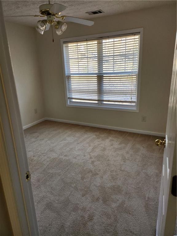 unfurnished room featuring carpet floors, visible vents, plenty of natural light, and a textured ceiling