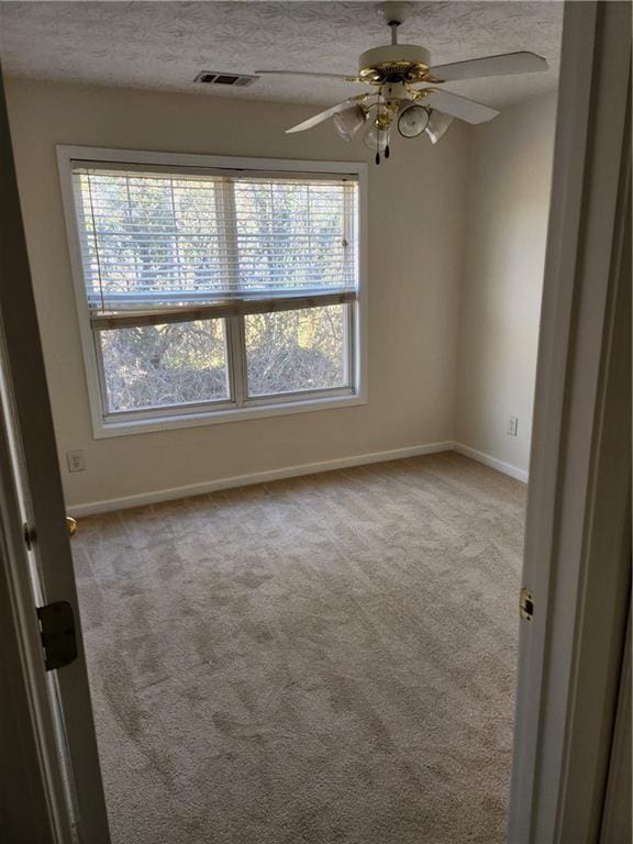 unfurnished room featuring carpet floors, visible vents, a textured ceiling, and baseboards