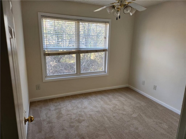 carpeted empty room featuring a ceiling fan and baseboards