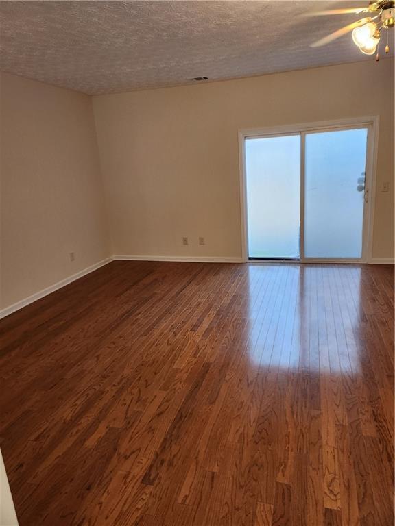 unfurnished room with dark wood-style floors, a textured ceiling, and baseboards