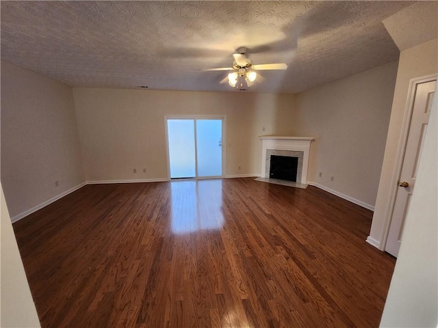 unfurnished living room with baseboards, a ceiling fan, dark wood-style floors, a premium fireplace, and a textured ceiling