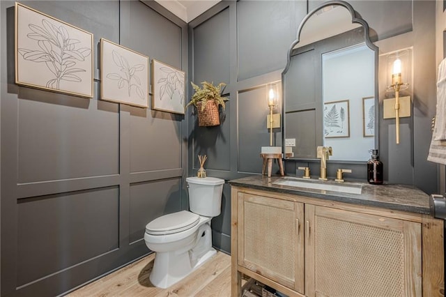 6301 New Bethany Rd, Buford, GA 30518 - bathroom featuring toilet, vanity, wood finished floors, and a decorative wall