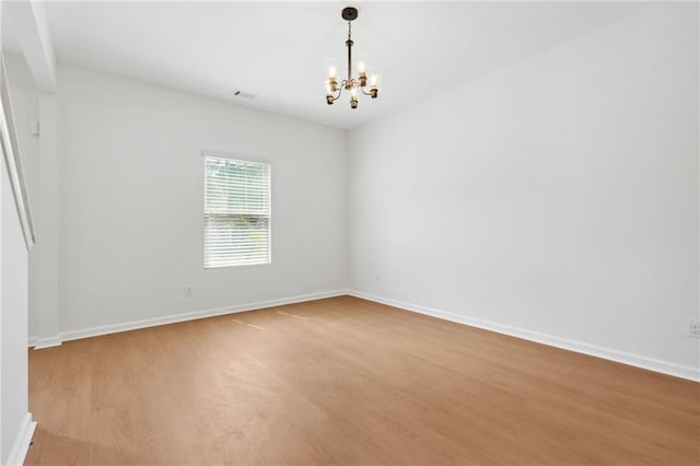 spare room with a chandelier and light hardwood / wood-style flooring