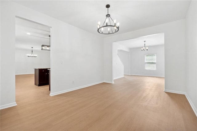 empty room with light hardwood / wood-style flooring and a notable chandelier