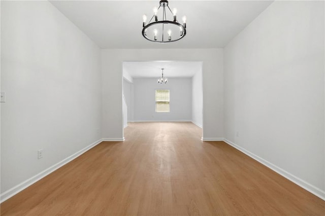 spare room featuring light hardwood / wood-style flooring and an inviting chandelier