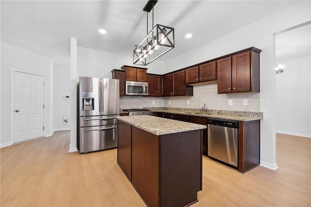 kitchen with pendant lighting, a center island, stainless steel appliances, and dark brown cabinets