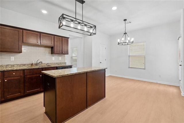 kitchen featuring light stone countertops, sink, a center island, light hardwood / wood-style floors, and hanging light fixtures