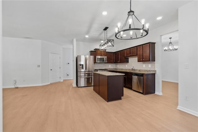 kitchen featuring pendant lighting, a kitchen island, light hardwood / wood-style floors, and stainless steel appliances